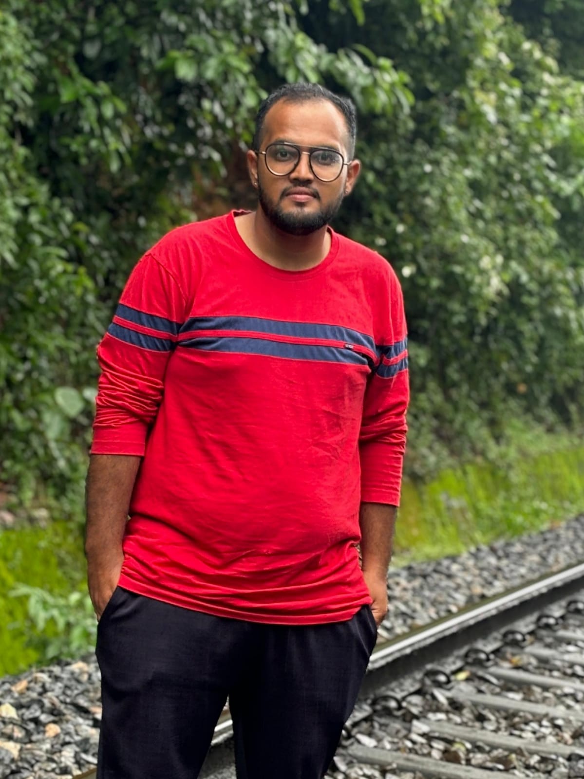 Dhanush P. Soorya standing outdoors in a red shirt.